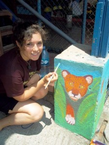 Paige Triola ’14 paints a mural at a local school.