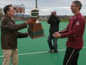 Field hockey head coach Andrew Griffiths receives the Patriot League Championship trophy from Lafayette President Daniel H. Weiss.