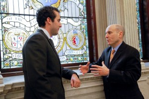 Scott Gelbman ’13 and Paul Brodeur ’86 speak by a stained glass window at the Massachusetts State House.