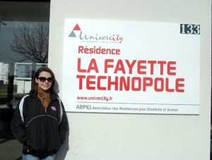 Rebecca McIver ’15 stands by a poster outside Résidence Lafayette in Metz