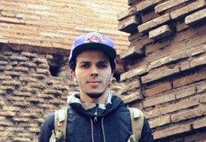 Joel Vargas '14 wearing a Cleveland Indians baseball cap in front of a building