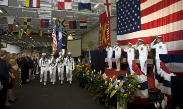 With military personnel saluting and carrying the American flag while an audience watches, Capt. Roth takes command of the USS Harry S. Truman in August 2012.