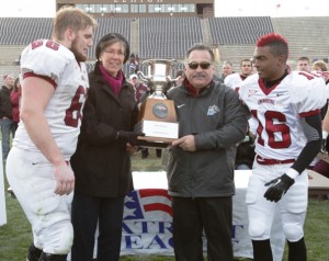 Offensive lineman Brad Bormann ’14, left, head coach Frank Tavani, and defensive back Randall Logan ’14 are presented with the Patriot League Championship trophy.