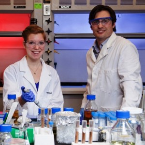 Wearing lab coats, Elizabeth Troisi '14 and Professor Justin Hines work in the laboratory.