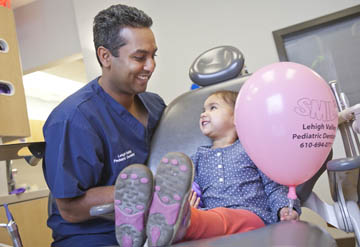 Dr. Amith Majumdar '95 with a young patient holding a pink balloon