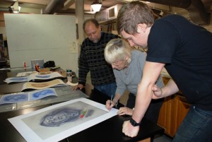 Professor Curlee Holton, painter Audrey Flack, and Jase Clark, master printer in training, look over a final proof.