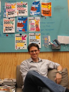 Lucas Reilly '13 sits in front of a bulletin board at the Mental Floss office