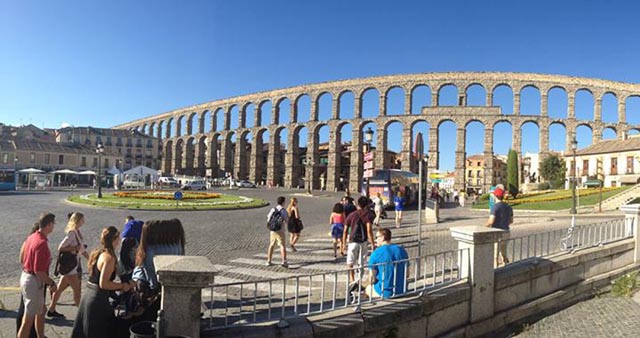 Youth walk by the Roman aqueduct in Segovia, Spain