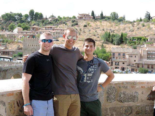 Victor D'Ascenzo '17, Christer Hoeflinger '17, and Scott Oliveri '17 pose in front of a wall in Madrid, Spain, with city buildings and land behind them