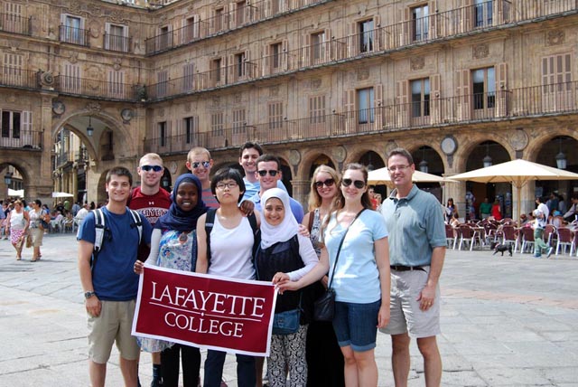 Professor Ethan Berkove and Lafayette students from the semester in Madrid program pose for a picture in the city as 3 students hold a Lafayette College banner