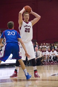 Dan Trist holds the ball above his head while being defended by an American University player.