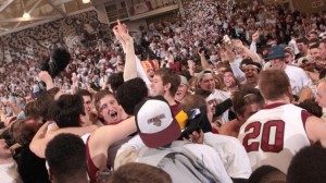 Men's basketball players and fans celebrate on the court