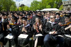 Graduates with caps and gowns applaud during Commencement in 2014.