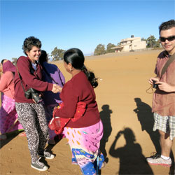 A Lafayette student shakes hands with an Indian woman while another student stands nearby with camera in hand