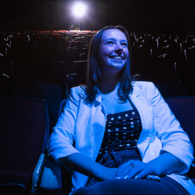 Annie Krege smiles in a dimly lit auditorium.