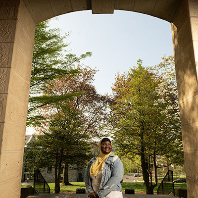 Fatimata Cham smiles, standing under an archway of Pardee Hall.
