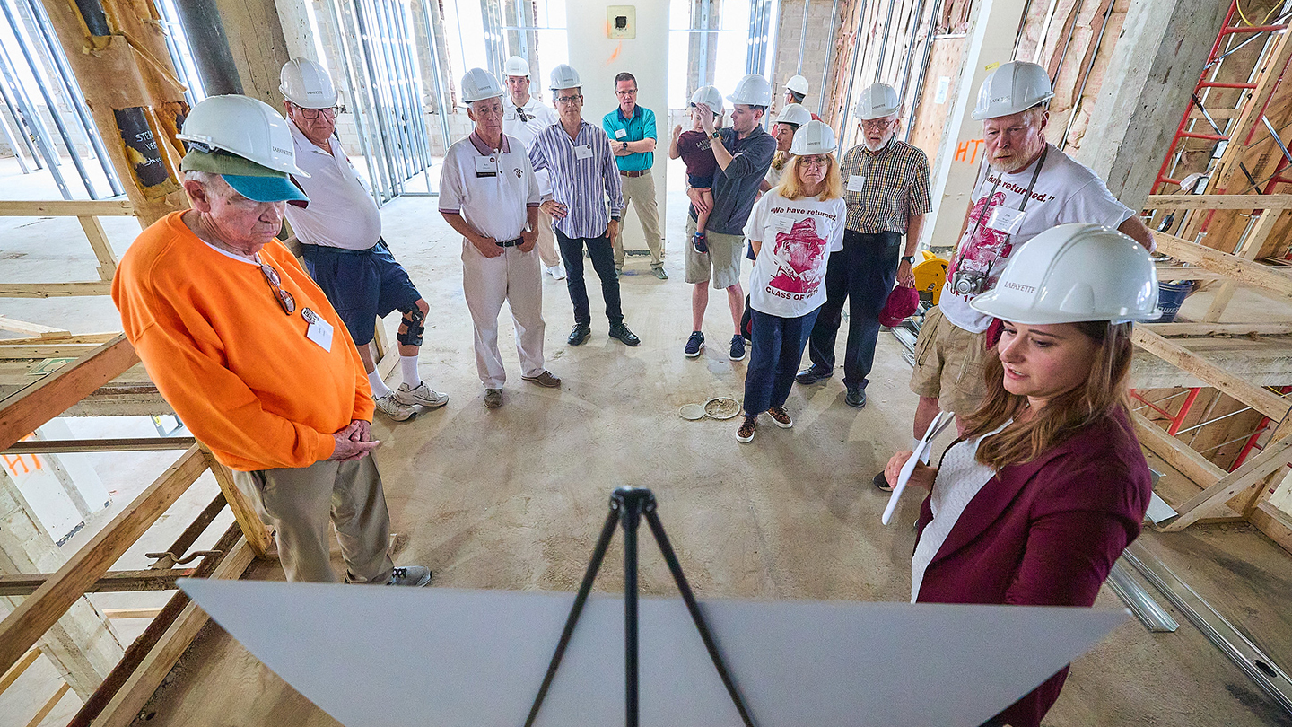 A staff member shares information at a hard hat tour of the new Simon Center for Economics and Business