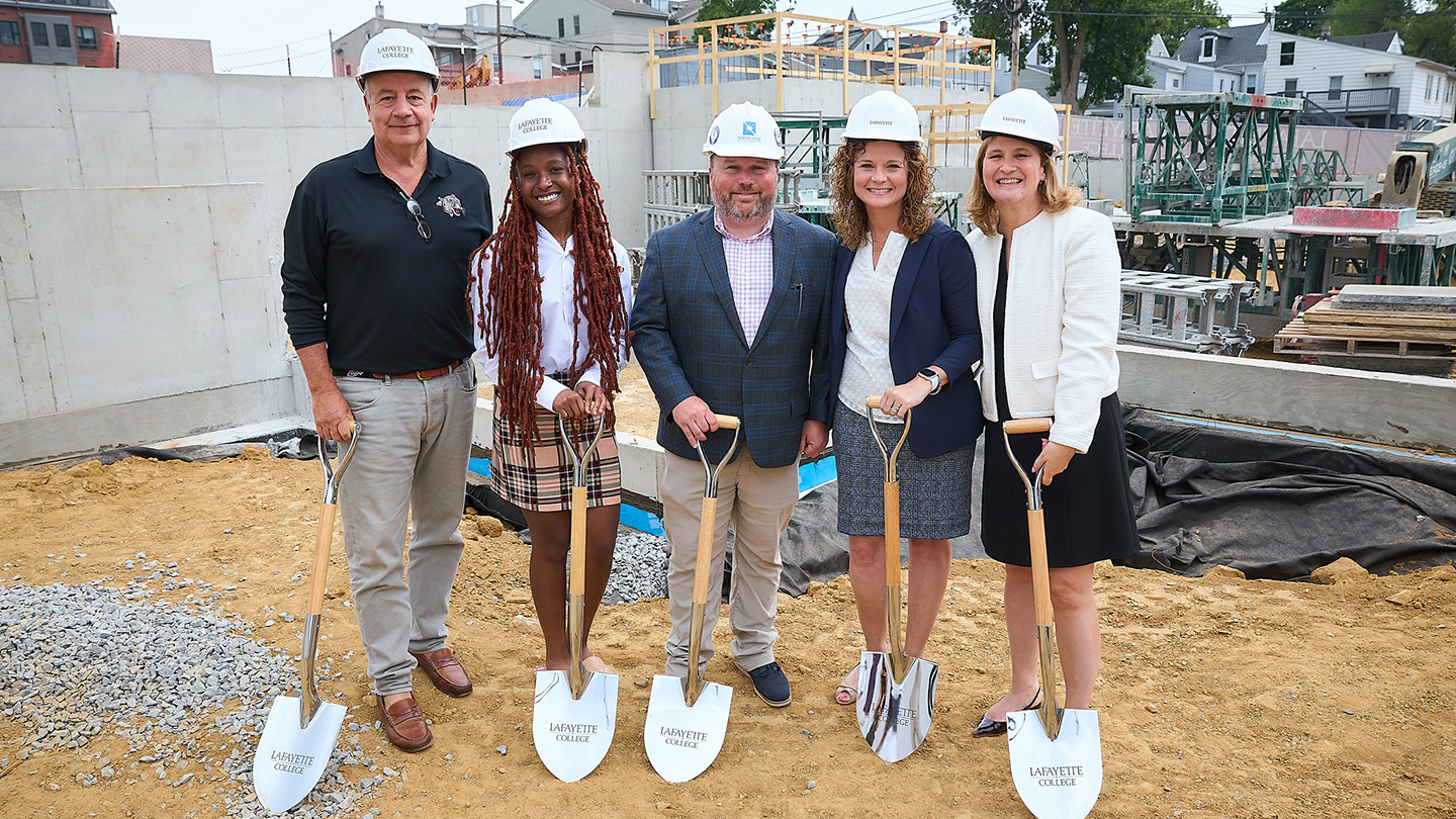 Robert E. Sell '84, board chair; Jada Peters '24, Andrew Miller, executive vice president, North Star Construction Management, Inc.; Audra Kahr, executive vice president, Finance & Business Administration; and Nicole Hurd, Lafayette president, broke ground for phase two of the McCartney Street housing complex during Reunion. The group is standing outside at the construction site. 