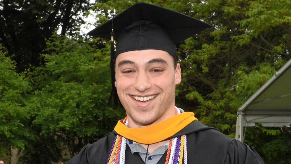 Jeremiah Alterman smiles, wearing a cap and gown.