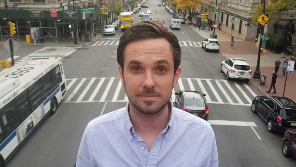 Headshot of assistant professor of government and law Dylan Groves with New York City street in the background