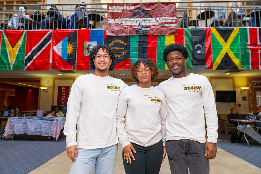Three students wearing Association of Black Collegians (ABC) tshirts smile in Farinon College Center.