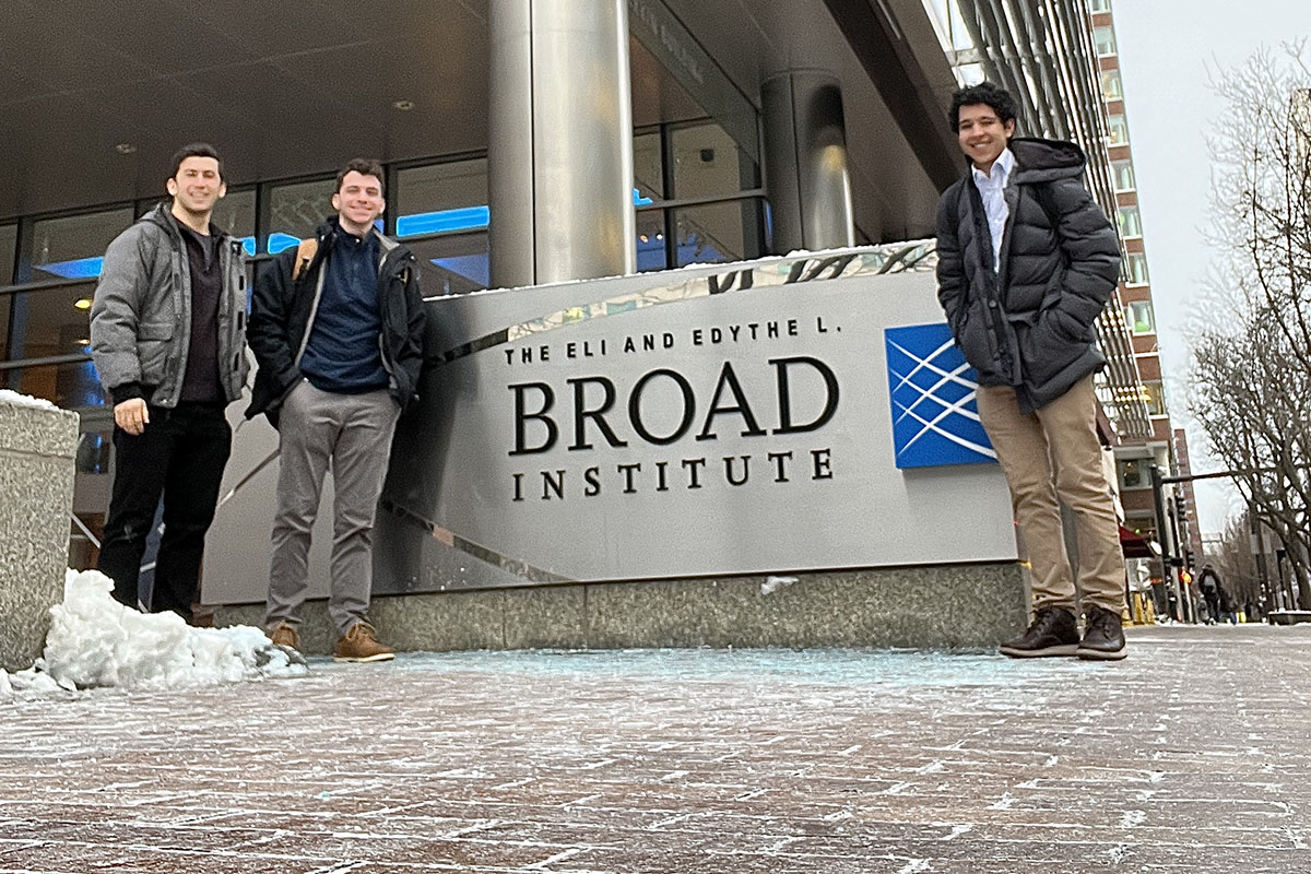 Nicholas Kolker ’25 and Luca Gianakopoulos ’25 stand with Dan Goodman ’20 outside near the sign for The Broad Institute