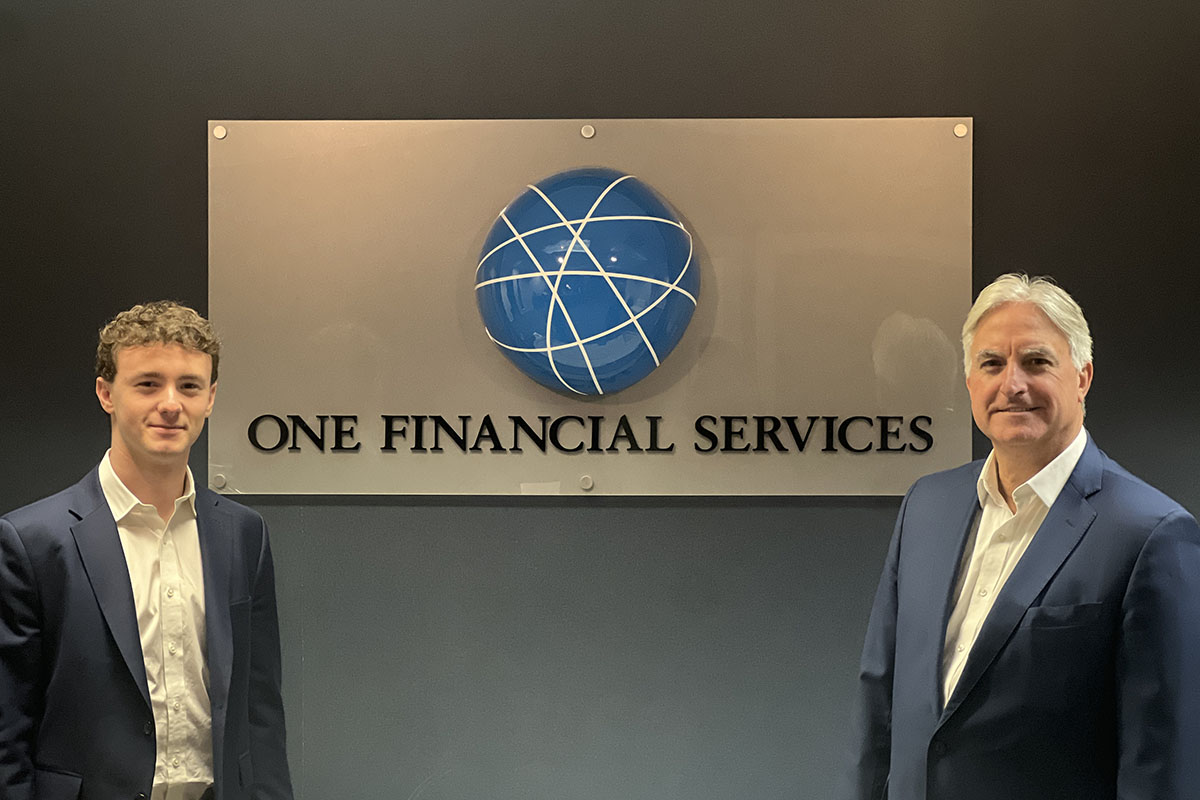Jack Morrone P’14 and Joseph White ’25 pose in front of the One Financial Services sign