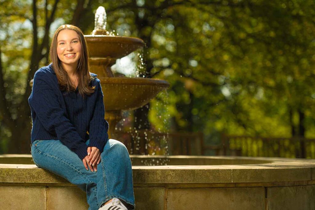 Alexa Raxenberg is photographed seated at the edge of a fountain