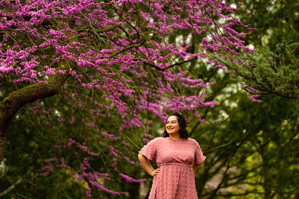 Michala Dennis is photographed amid a purple tree in bloom