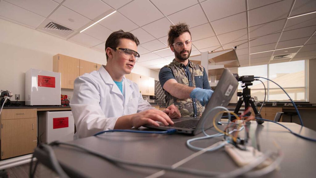 Professor Ryan Rosario and student-researcher Jack Blackmar working in a research lab