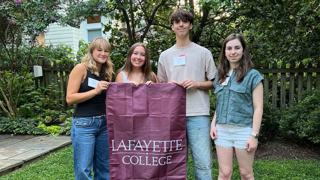 Incoming members of the Class of 2028 from the greater Washington D.C. area are smiling at the camera. They are holding a Lafayette flag.