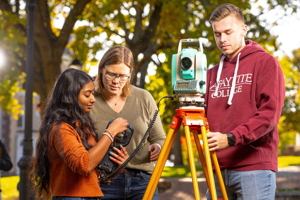 Two students and a professor work on campus.