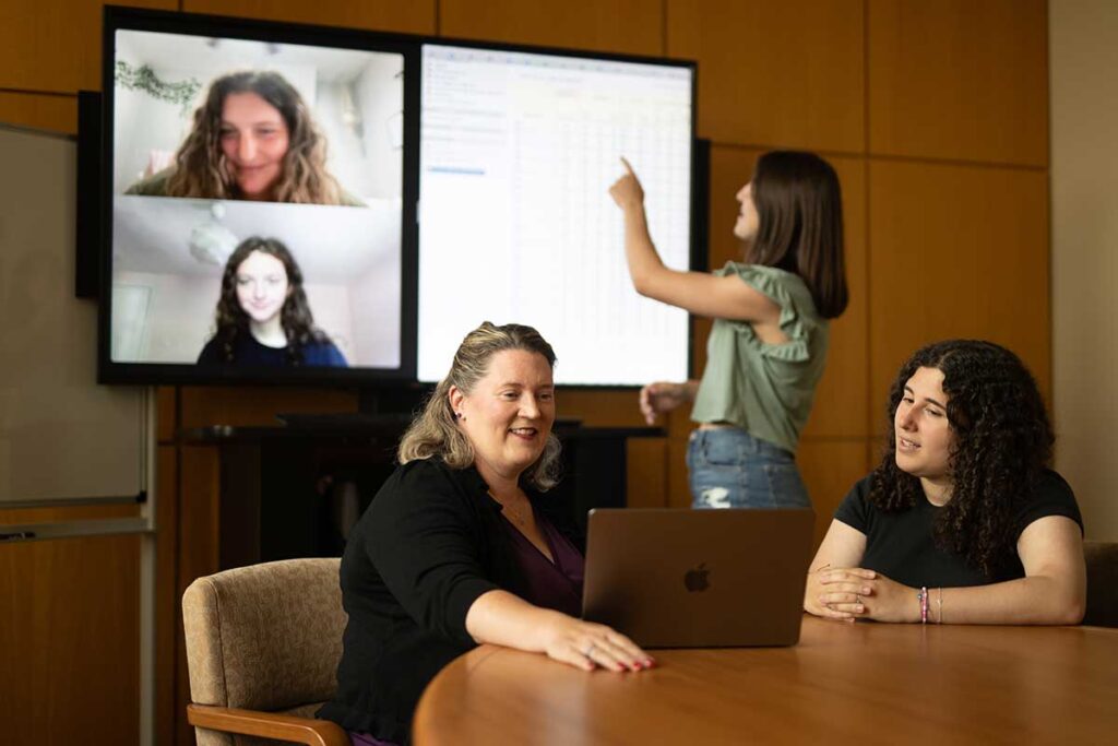 Professor Lauren Myers discussing research project with students Caroline Hugo ’25, Hayley Katz ’25, Samantha Montague ’26, and Gabriela Pedulla ’26 in a conference room