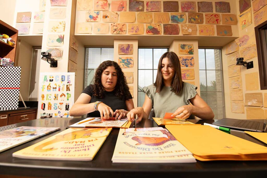 Samantha Montague '26 and Gabriela Pedulla '26 preparing packets of books to be mailed to grandparents and grandchildren participating in their research study