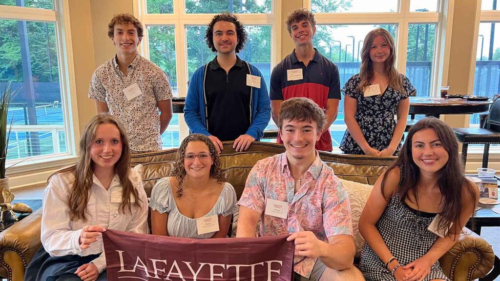 Incoming members of the Class of 2028 from Philadelphia are smiling at the camera. They are holding a Lafayette flag.