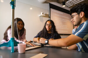 Three students smile at a table