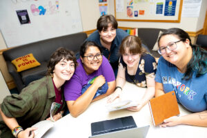 Four students and a staff member sit in the Gender and Sexuality Resource Center