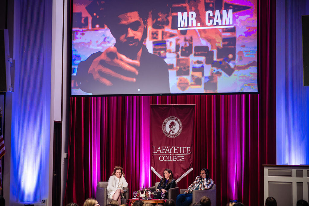 President Nicole Hurd, Jaye Fenderson, and Daveed Diggs speak on stage in Colton Chappel as a preview of The Class is shown on screen.