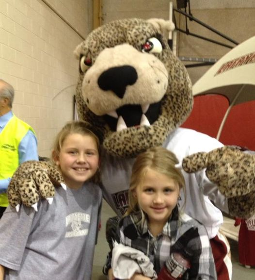 Lillian Hercik ’27, as a young child, poses with the Leopard mascot and another individual. 