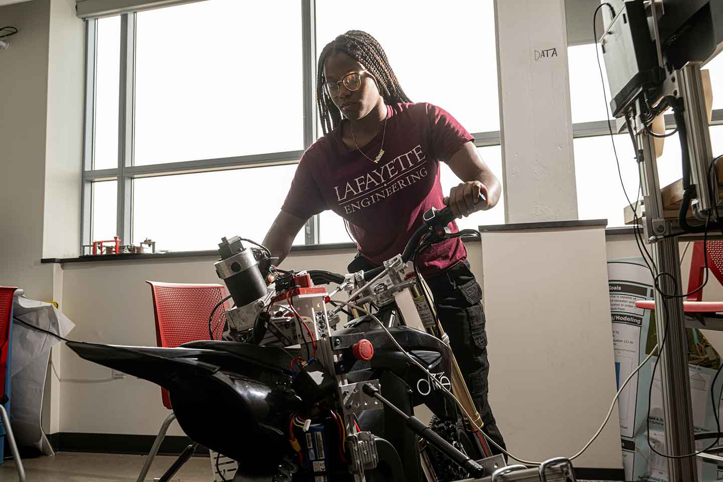 Paris Francis '26 adjusts the handlebars of a motorcycle.