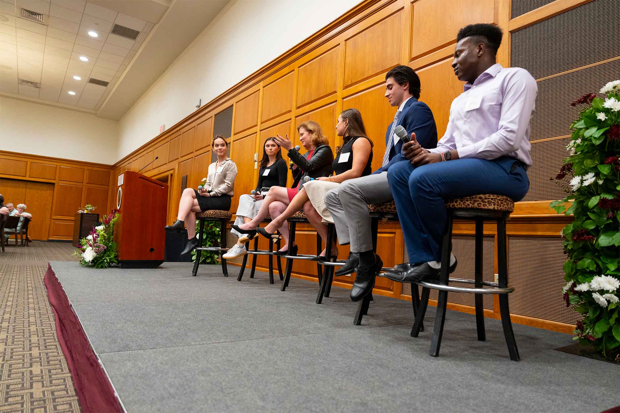 President Hurd is seated in the center of five students who are on stage participating in a panel discussion.