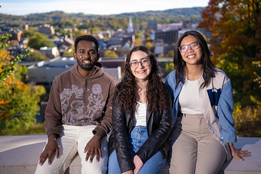 Three students smile in front of a view of downtown Easton