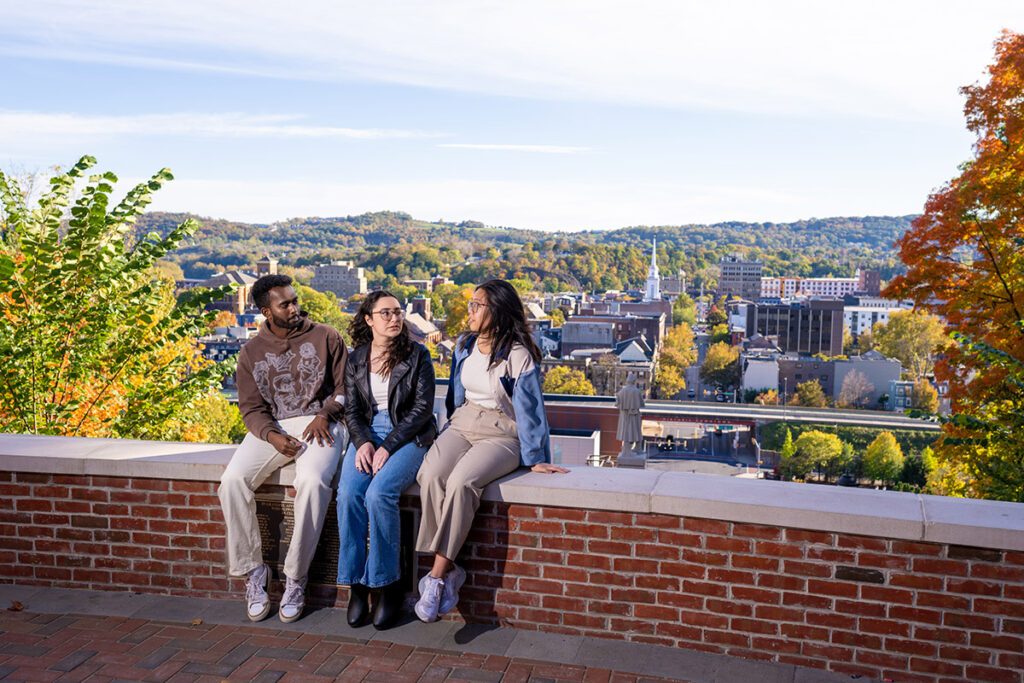 Areeb Atheeque ’25, Naya Kurdy ’25, and Kelsey Wong ’25 sit on a ledge overlooking Downtown Easton