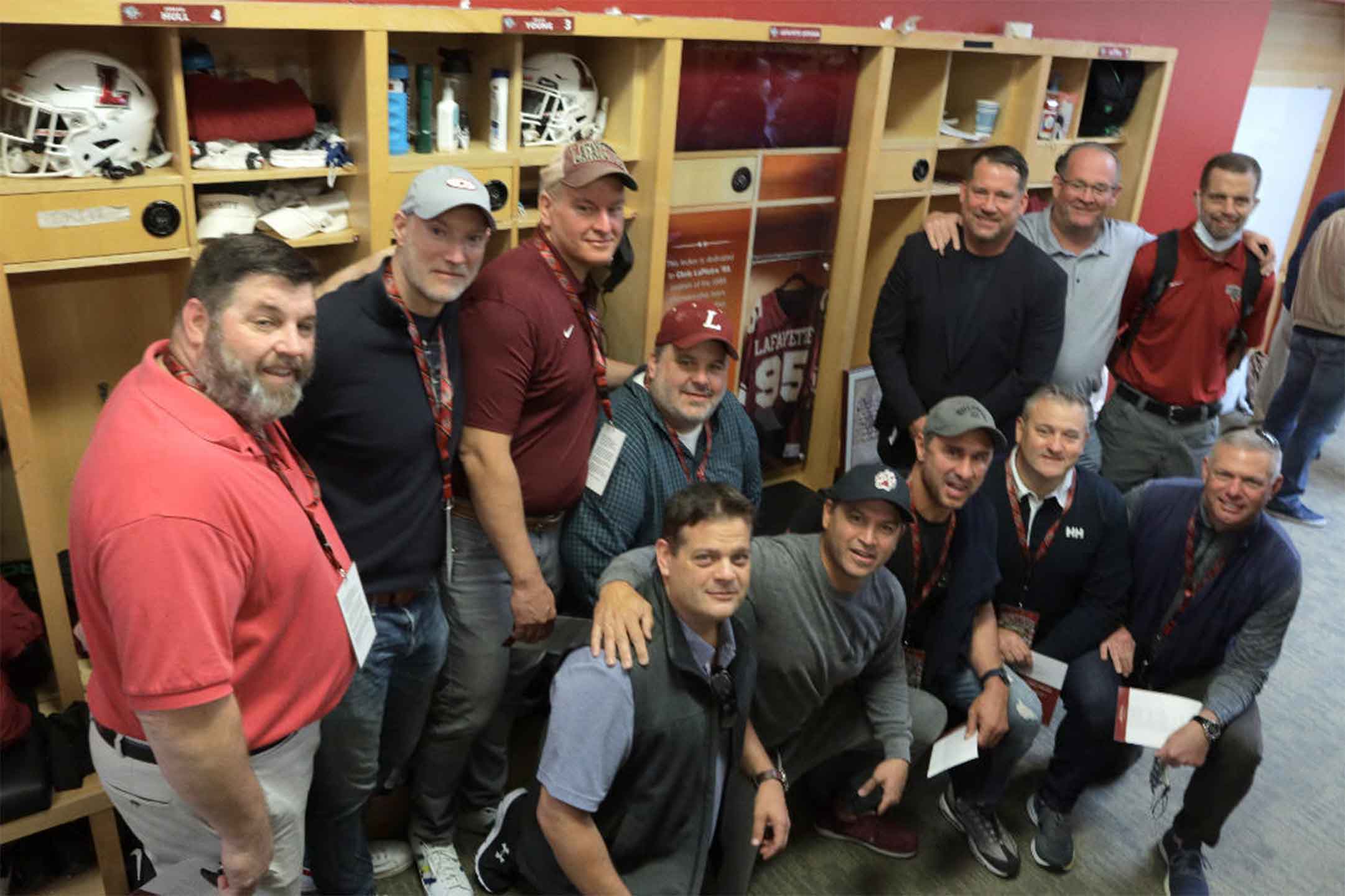 Members of the 1988 conference championship football team gather in the locker room to honor former teammate Chris LaPietra '89. They are standing by a locker that honors LaPietra.