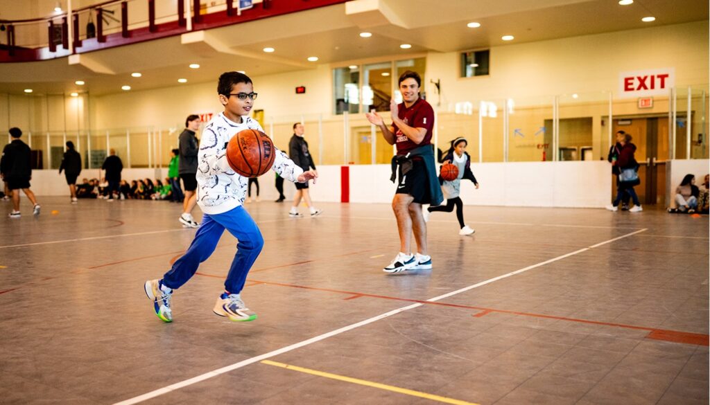 An Easton student dribbles the basketball as a men's lacrosse player cheers him on. (Photos by Adam Atkinson)