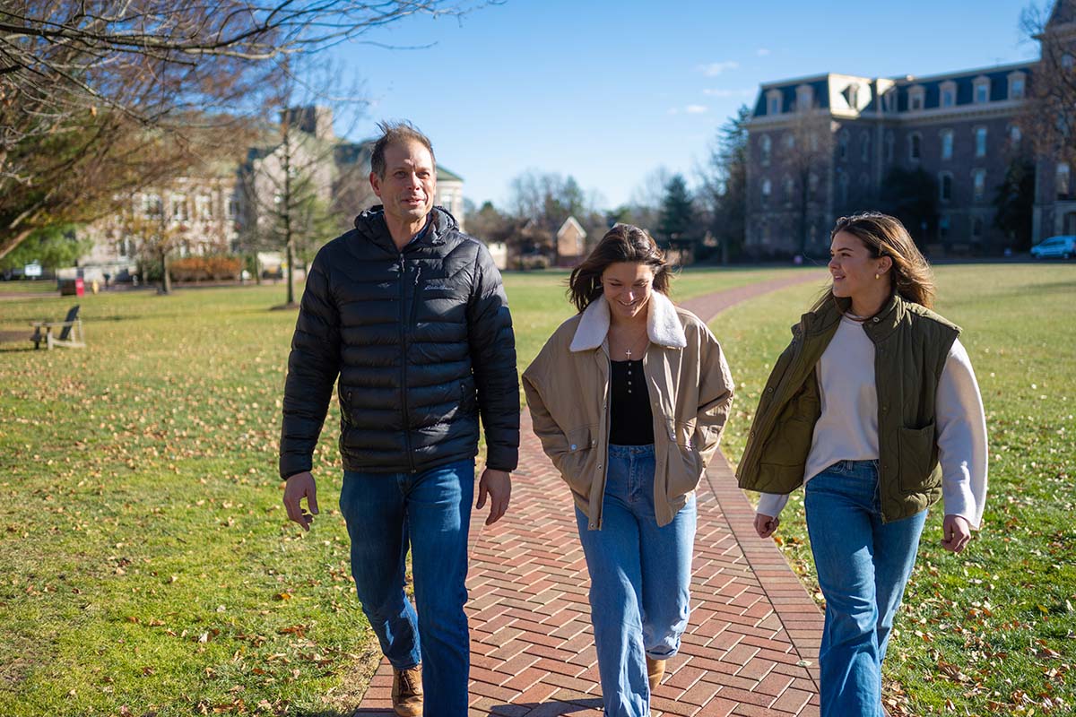 Dave Sunderlin, Kate Marrs and Ellie Spencer walk on the Quad