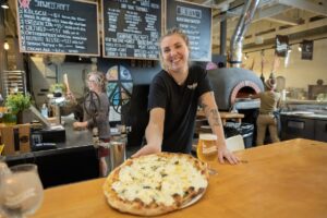 A woman holds a pizza from Scratch Easton