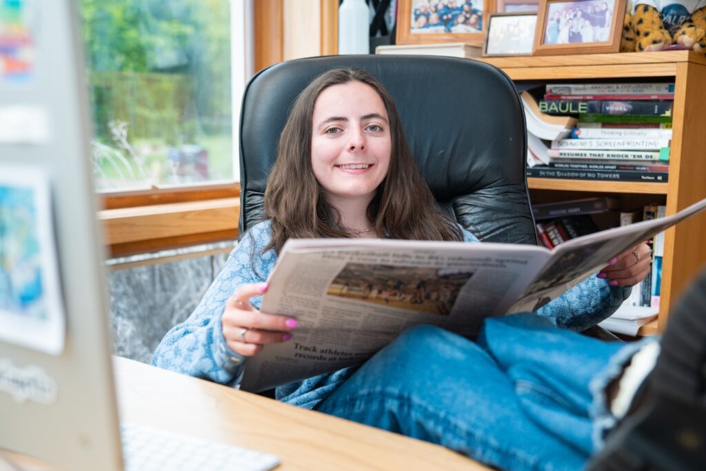 Isabella Gaglione '25 sits with her feet up on the desk reading a copy of The Lafayette