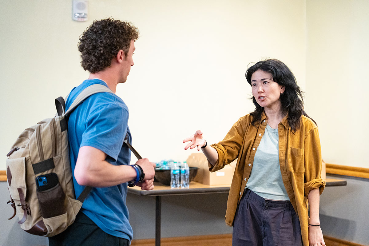 Lisa Sanaye Dring speaks to a student in a lecture hall.