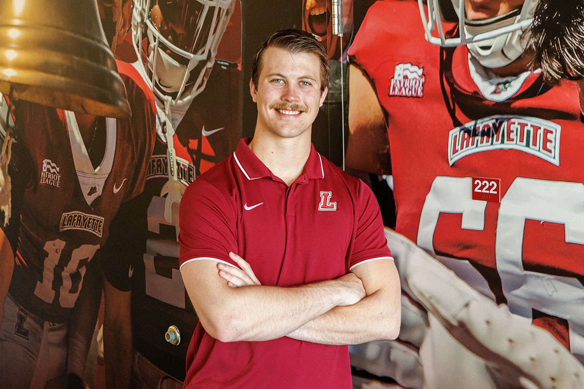 Tyler Roberts '25 stands in front of a wall depicting Lafayette football players.